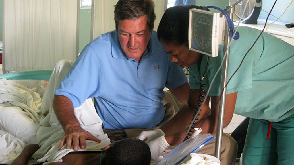 Father Rick Frechette tends to a patient at St. Luke's Hospital in Port au Prince, Haiti. (Photo courtesy of St. Luke Foundation)