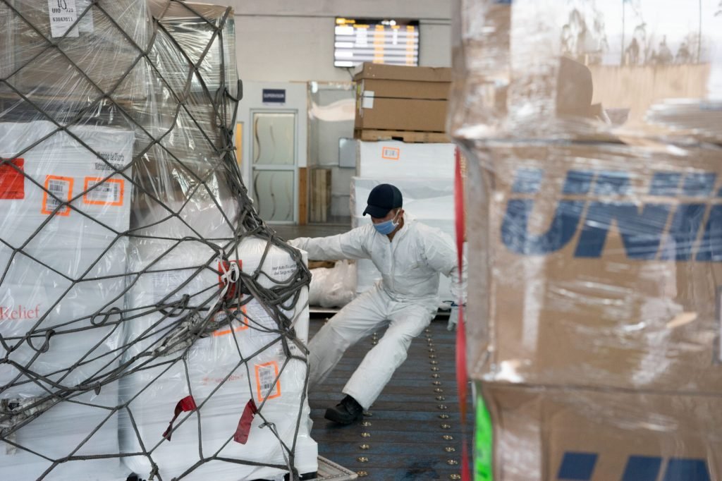 An Ecuadorian customs worker, with his transfer in Quito, removes the cover from the equipment delivered as a donation. (Isadora Romero for Direct Relief)